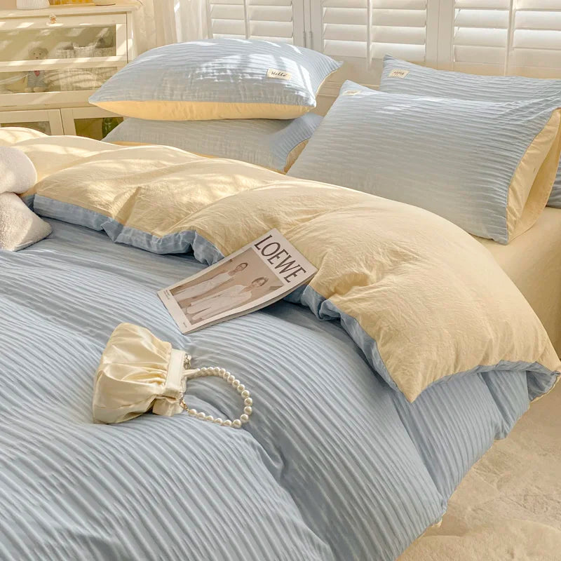 Beige and gray striped bedding set on a bed with a LOEWE magazine.