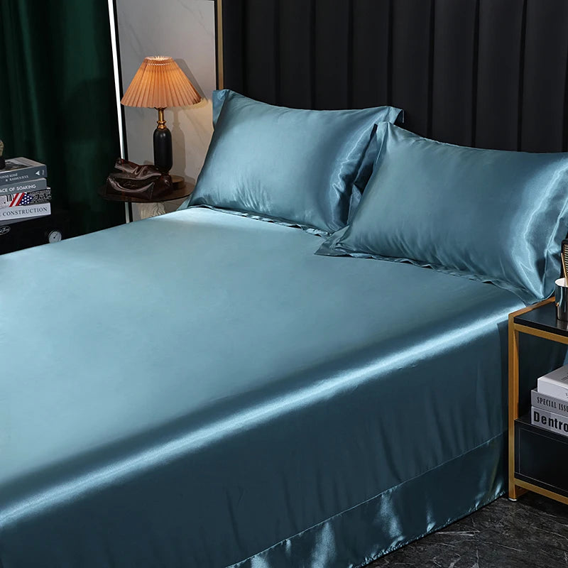 Teal satin bedding set on a bed with a lamp and books in the background.
