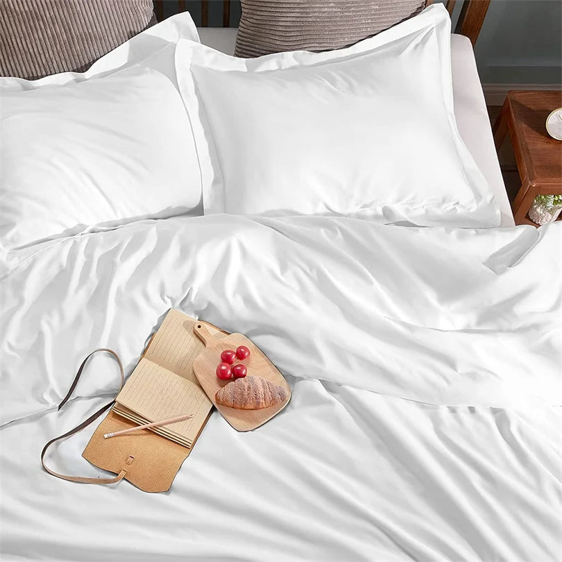 White satin pillowcases on a bed with a wooden tray and small items.