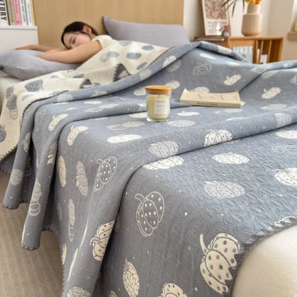 Person sleeping under a patterned gray blanket with a candle and book on a bed.