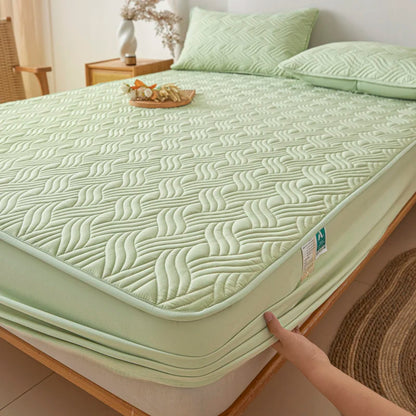 Green quilted mattress cover on a bed in a bedroom setting