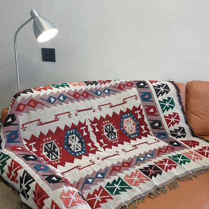 Decorative blanket with geometric pattern on a couch next to a lamp.