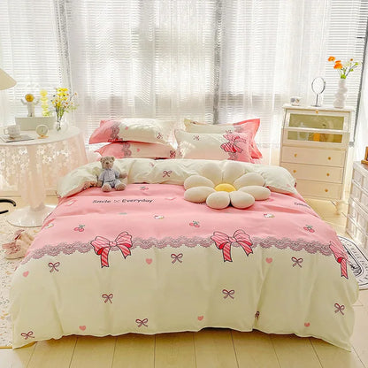 Pink and white floral bedding set with decorative pillows and a teddy bear on a bed in a bright room.