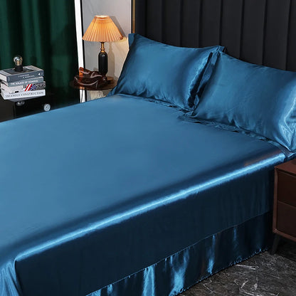 Blue satin sheet set on a bed with a lamp and books in the background.