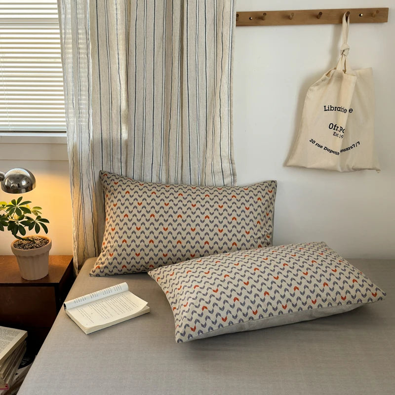 Patterned pillows on a sofa with a striped curtain and hanging bag in the background