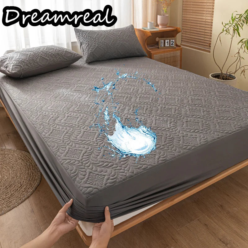 Gray mattress cover with water splash graphic on a bed in a bedroom setting, featuring the brand 'Dreamreal'.