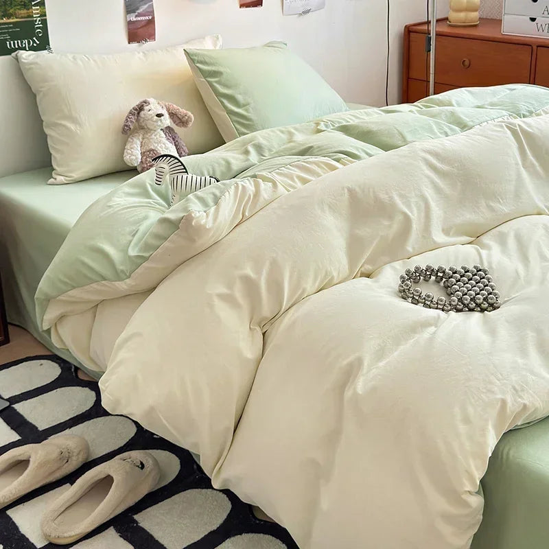 Neatly made bed with light green bedding and a white comforter in a bedroom setting.