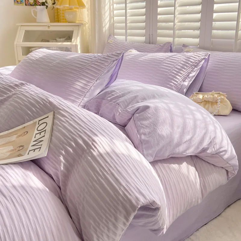 Purple striped bedding set on a bed with a visible brand name on a pillow.
