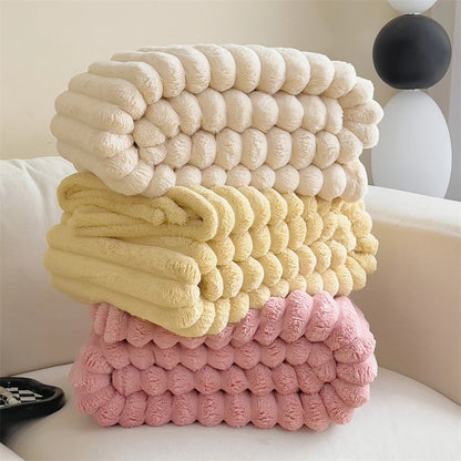Stack of textured pillows in beige, yellow, and pink on a couch.
