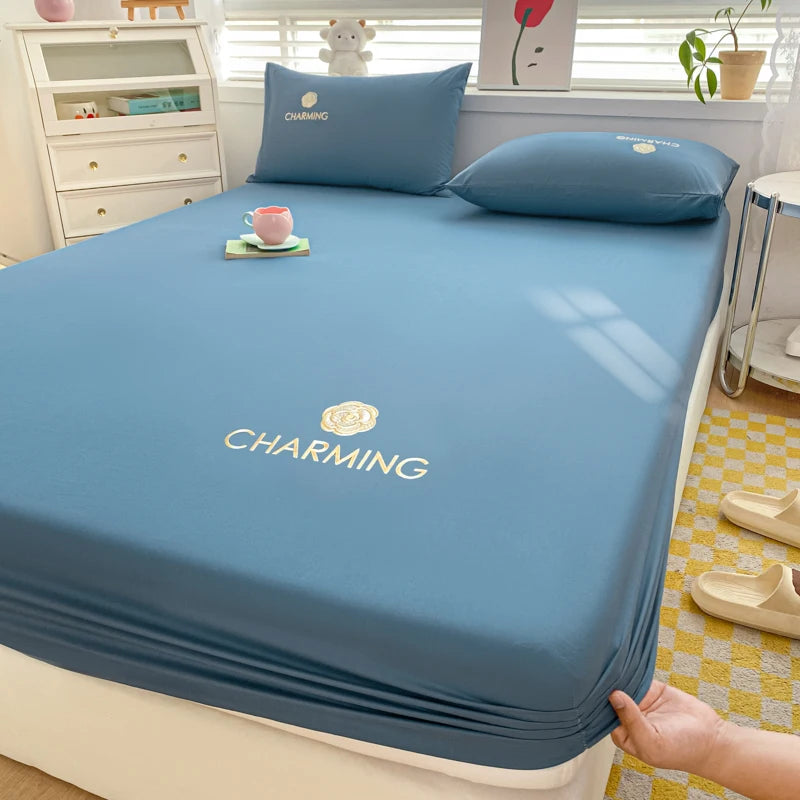 Blue bedsheet set on a bed with pillows and a cup in a bedroom setting.