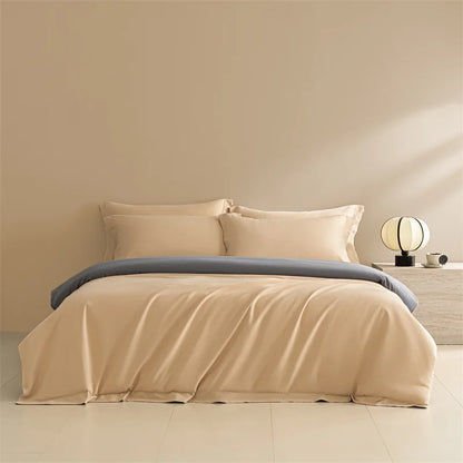 Beige bedding set with gray blanket on a bed in a minimalistic room.
