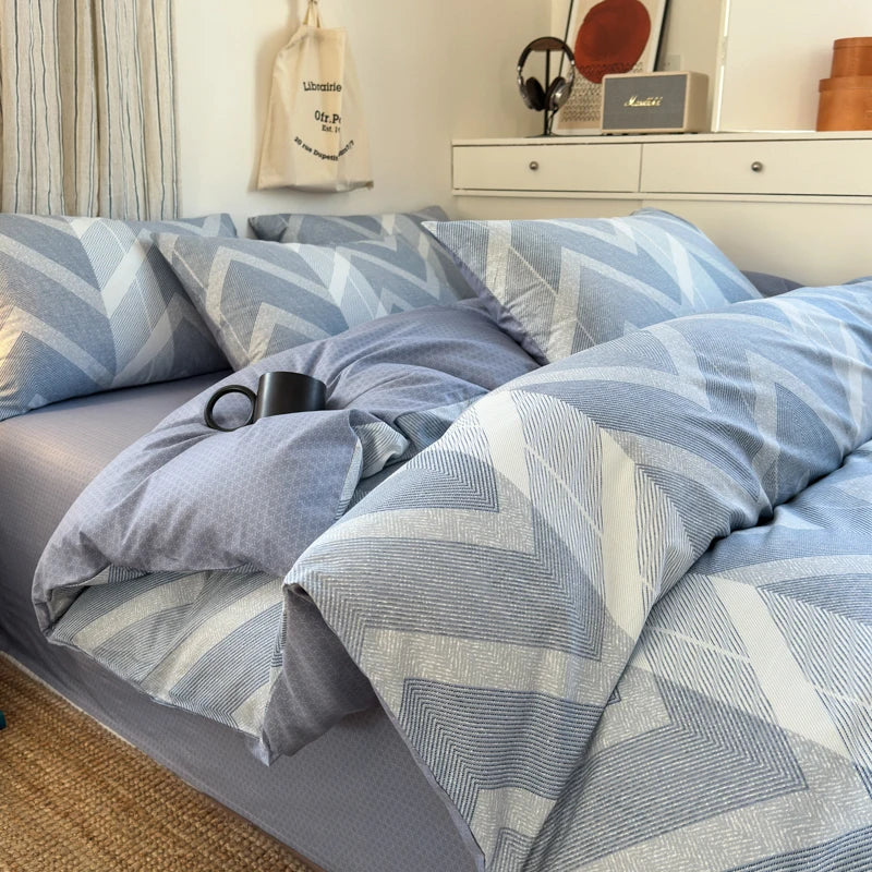 Blue geometric patterned bedding set on a bed in a bedroom.
