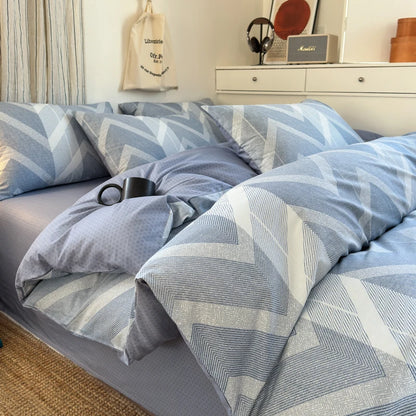 Blue geometric patterned bedding set on a bed in a bedroom.