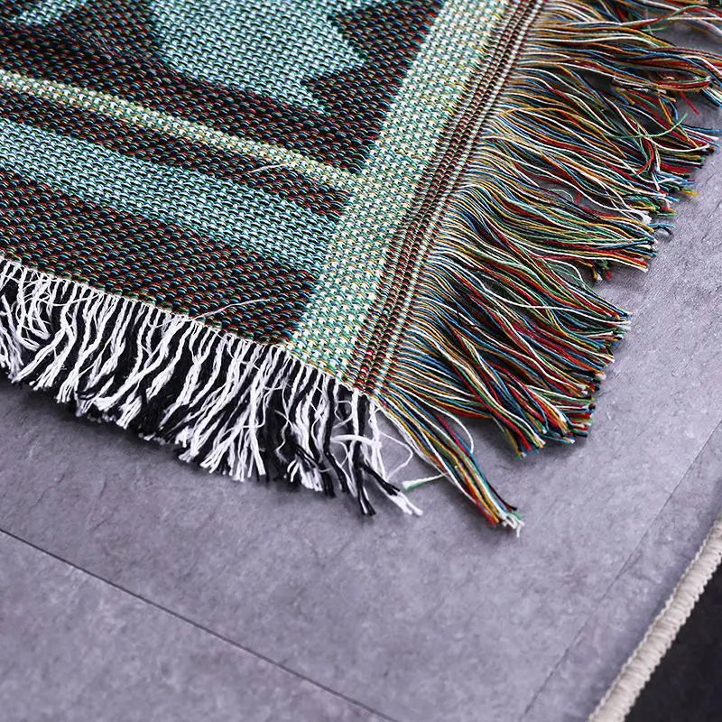 Close-up of a woven rug with colorful fringes on a gray floor.