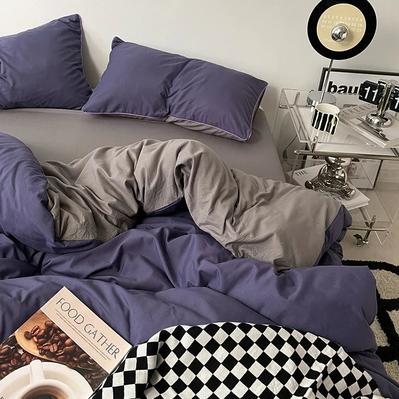 Bedroom with purple bedding and pillows, a nightstand with a lamp, and a record player.