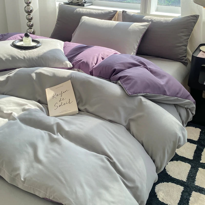 Gray and purple bedding set on a bed with a book titled 'Rafale de Soleil'.