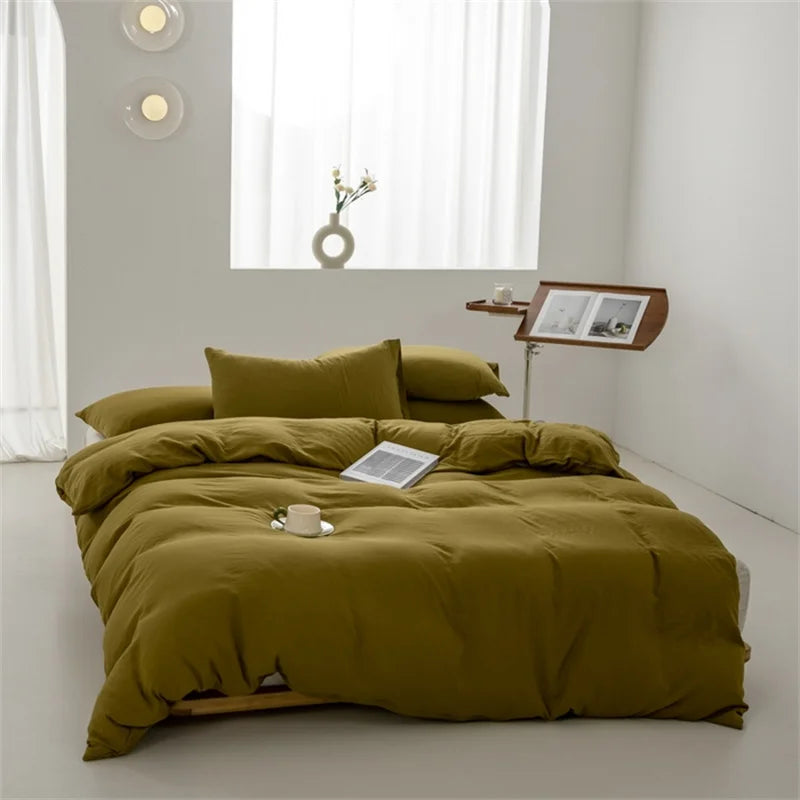 Green bedspread on a bed in a minimalistic room with a side table and window.