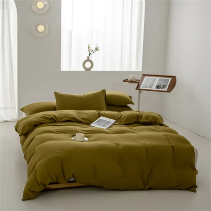 Green bedspread on a bed in a minimalistic room with a side table and window.