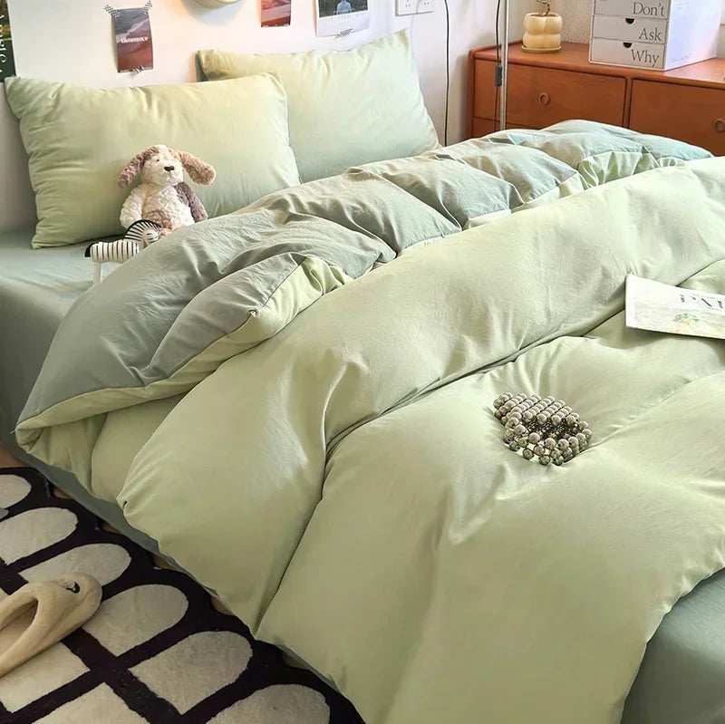 Light green bedding set on a bed with pillows and a teddy bear in a bedroom setting.