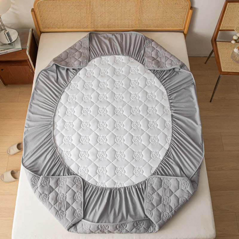 Gray quilted baby play mat on a bed with wooden headboard