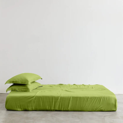 Green bed sheets and pillowcases on a bed against a white wall.