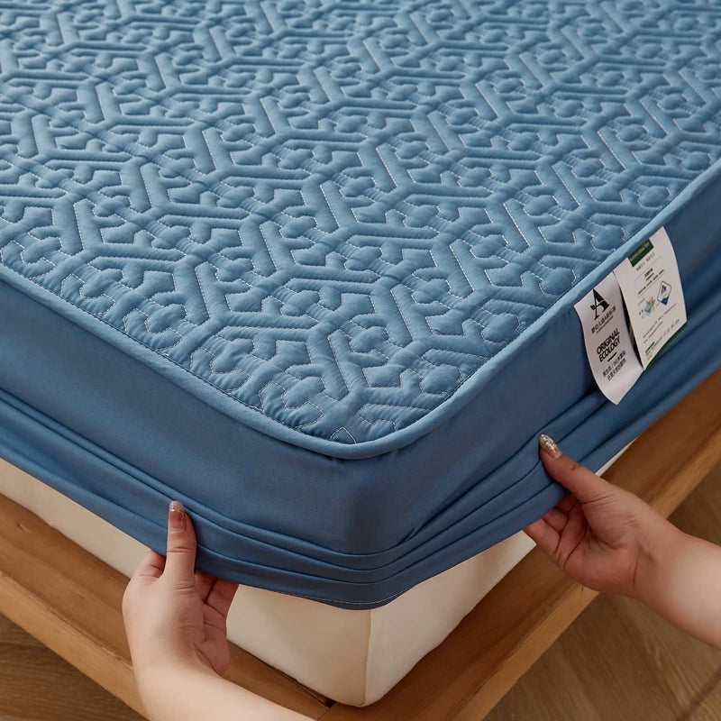 Blue mattress cover with geometric pattern being held by a person on a wooden floor.