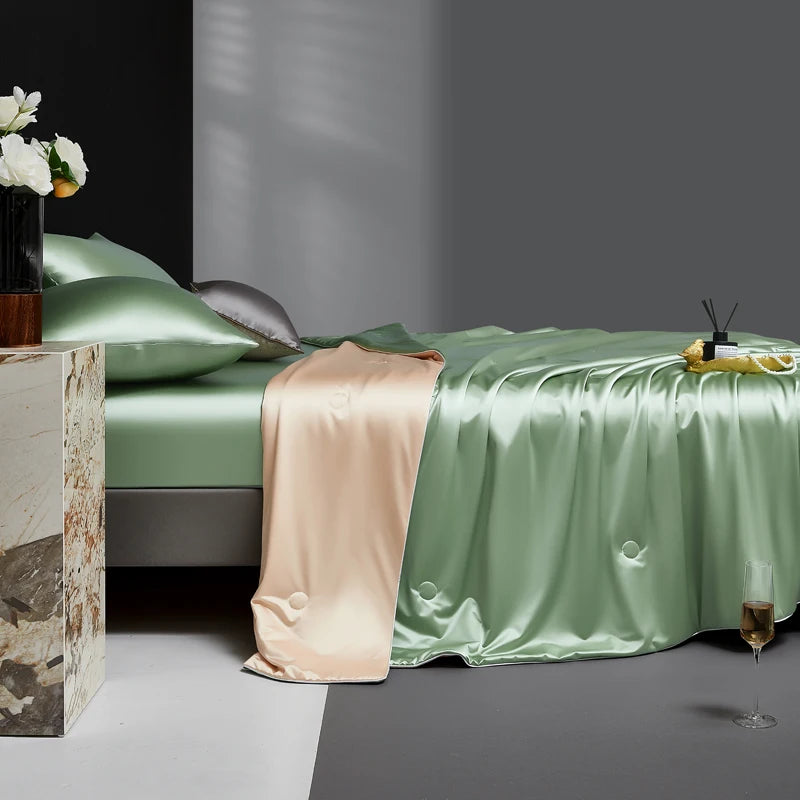 Green satin bedspread on a bed with a side table and decorative items.