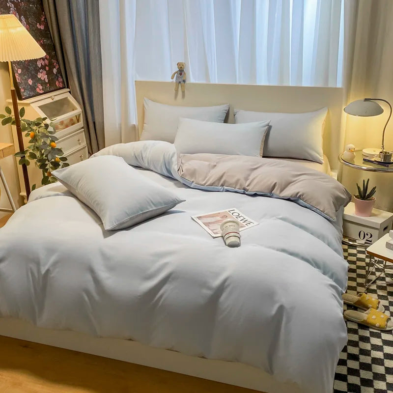 Neatly made bed with gray bedding in a bedroom setting.