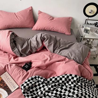 Pink and gray bedding set on a bed with a checkered blanket, in a room setting.