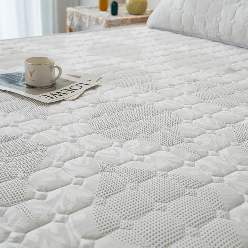White quilted mattress cover on a bed with a cup and newspaper on top.