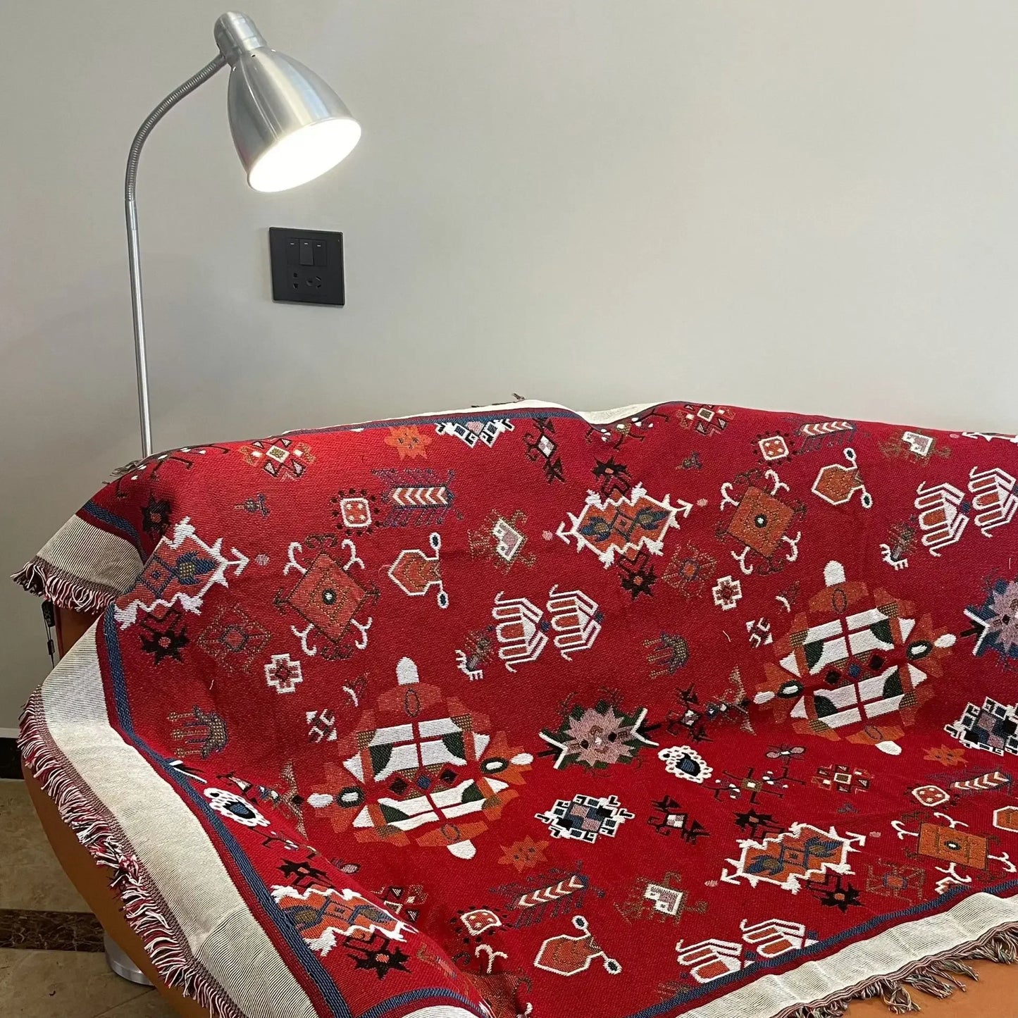 Red patterned blanket draped over a chair with a lamp in the background.