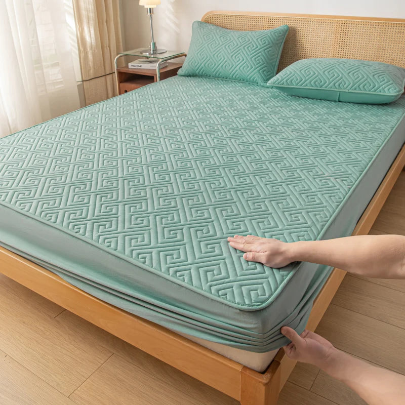 Person adjusting a green quilt on a bed in a bedroom setting
