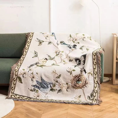 Decorative blanket with bird and floral pattern draped over a chair.