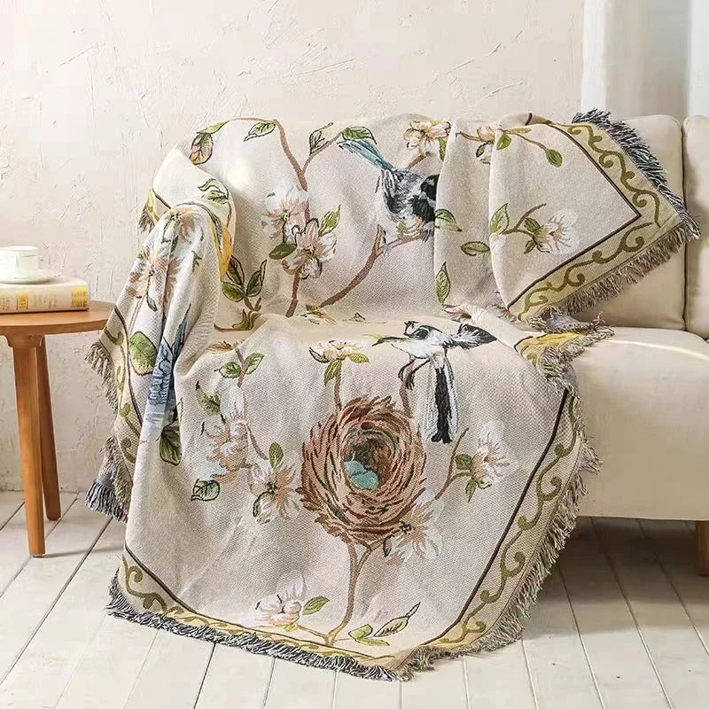 Decorative blanket with bird and nest design draped over a chair in a room.