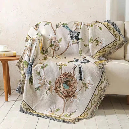 Decorative blanket with bird and nest design draped over a chair in a room.