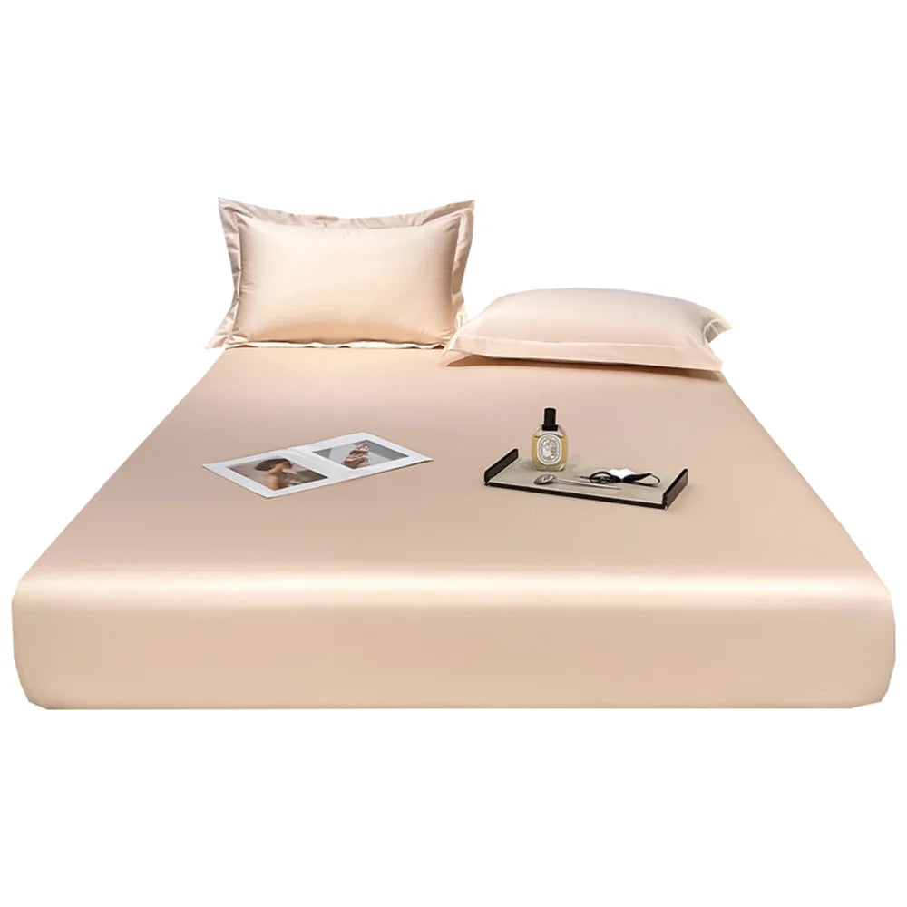 Beige satin sheet set with pillows on a white background