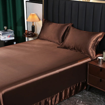 Brown satin bed sheets on a bed with matching pillows, in a bedroom setting.