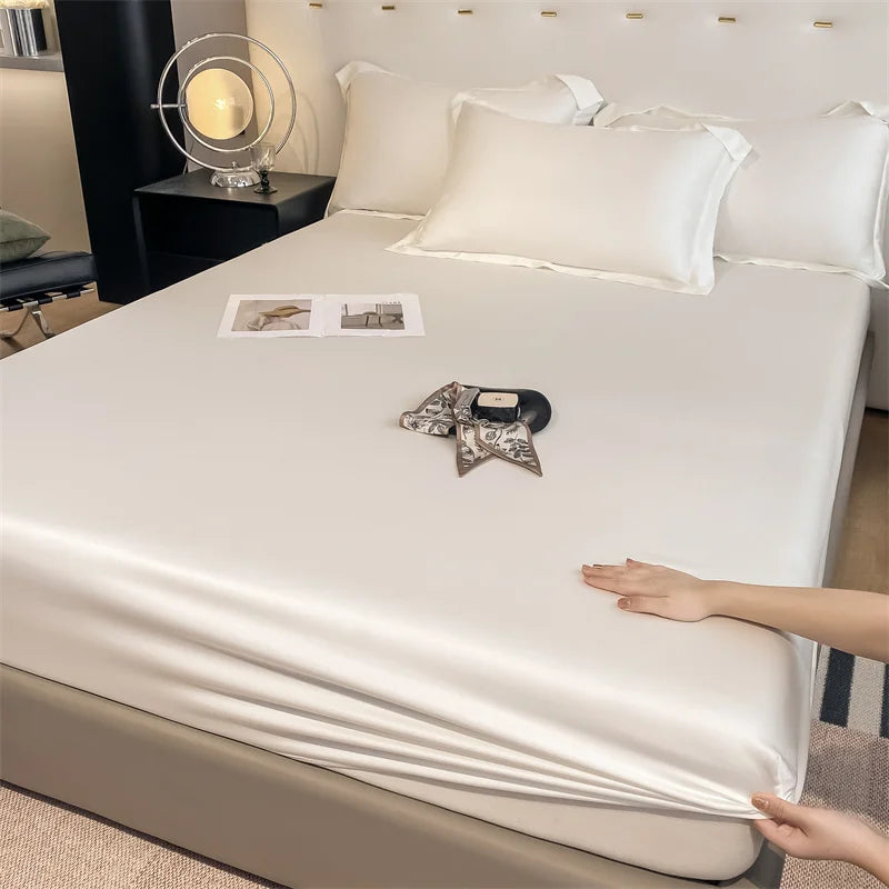 Person unrolling a satin sheet on a bed in a bedroom setting