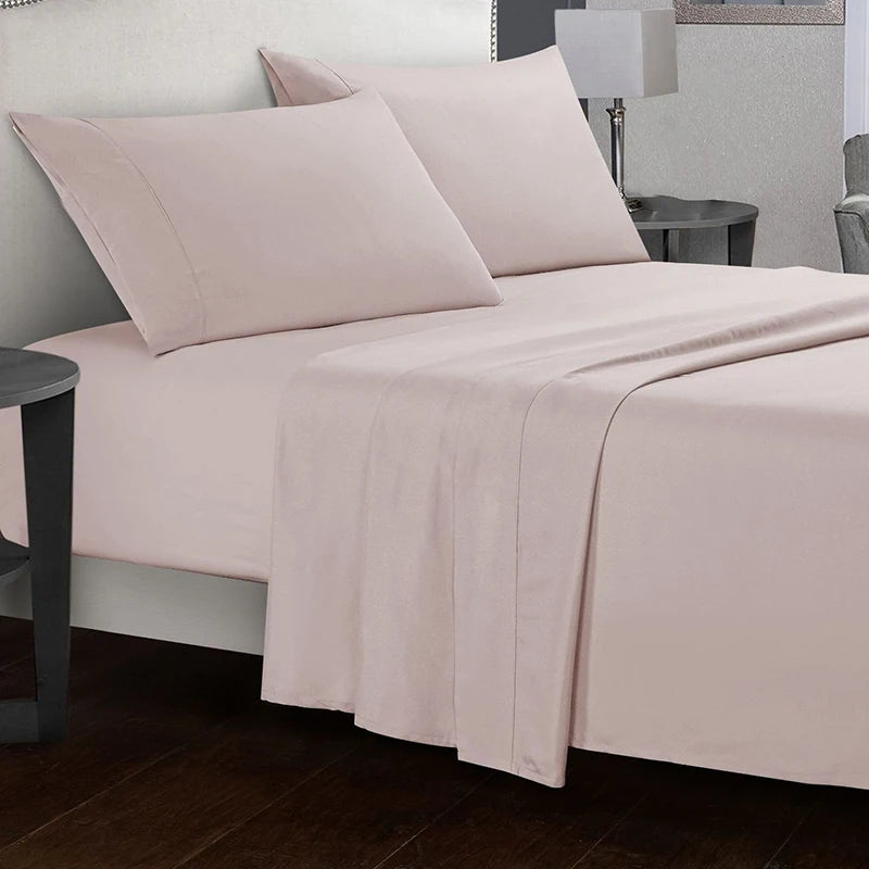 Neatly made bed with light pink bedding in a bedroom setting.