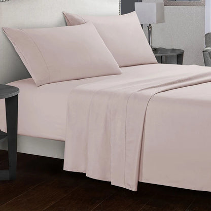 Neatly made bed with light pink bedding in a bedroom setting.
