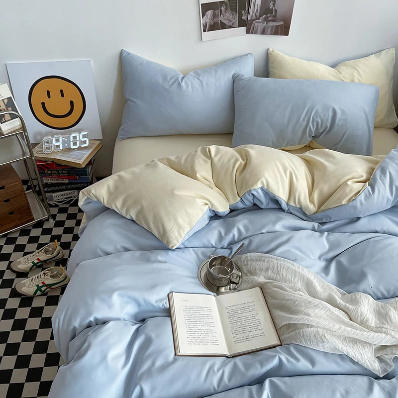Bed with light blue bedding and pillows, open book, and cup on a checkered floor.