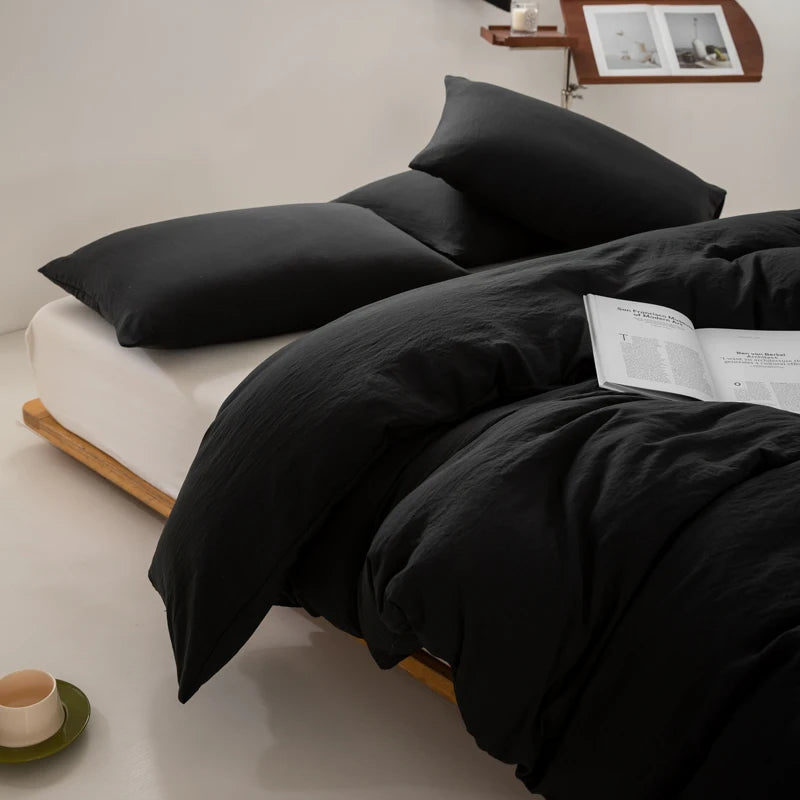 Black bedding set on a bed with a minimal background