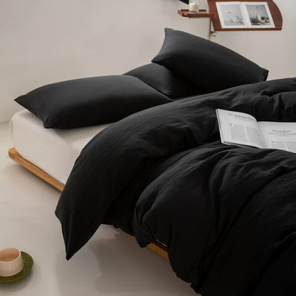 Black bedding set on a bed with a minimal background