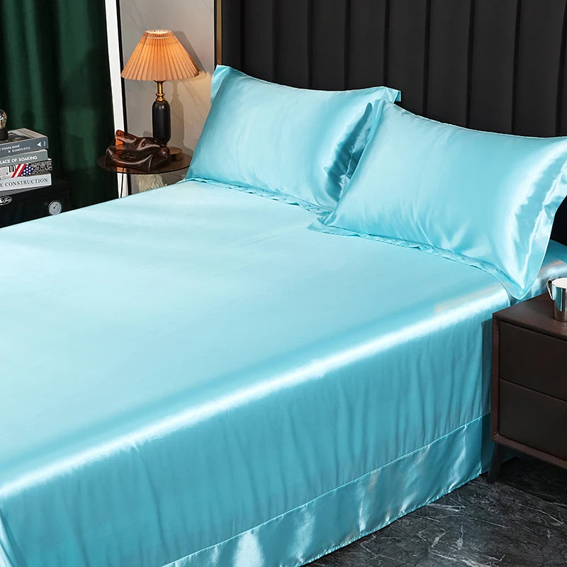 Turquoise satin sheet set on a bed with a lamp and books in the background.