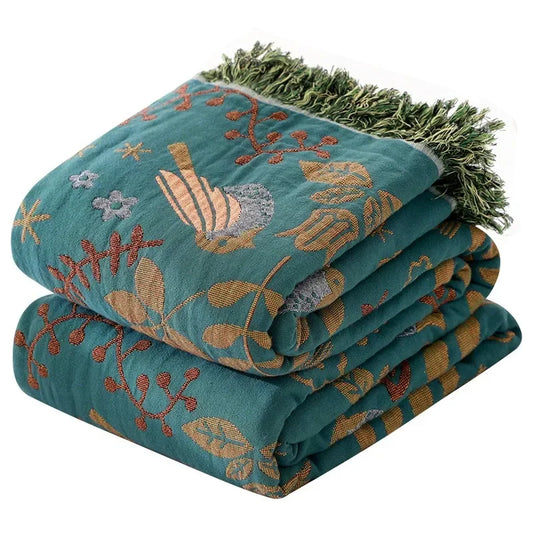 Folded teal blanket with floral patterns on a white background
