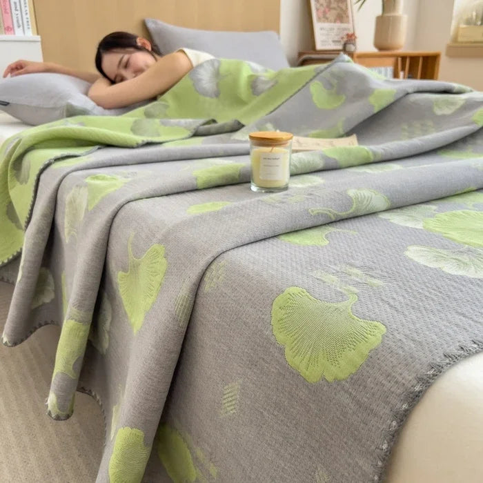 Person lying on a bed with a gray and green floral patterned blanket
