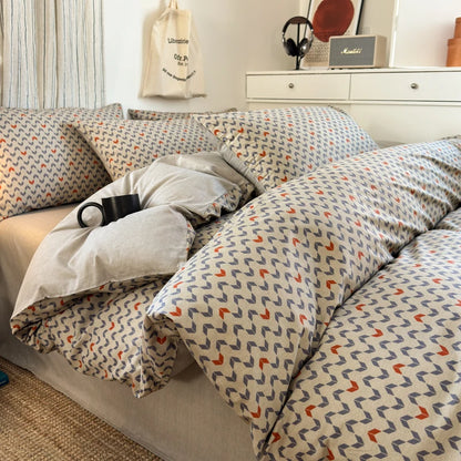 Patterned bedding on a bed in a room with a shelf and decor items.