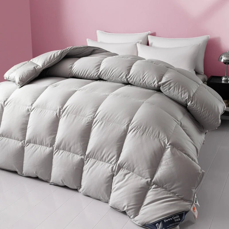 Gray comforter on a bed with white pillows against a pink wall
