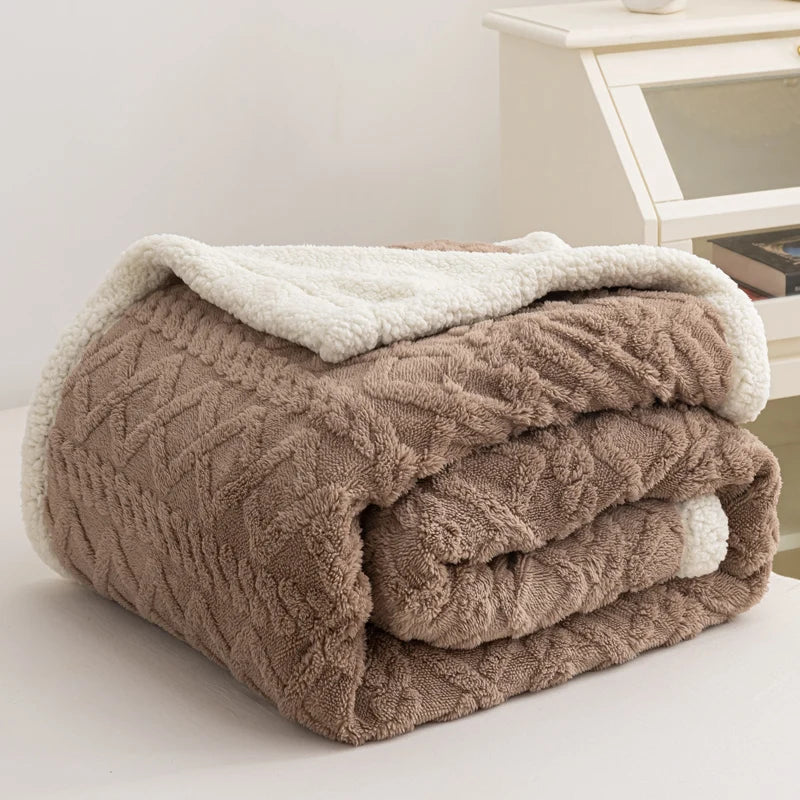 Folded brown cable knit blanket with white sherpa lining on a light surface.