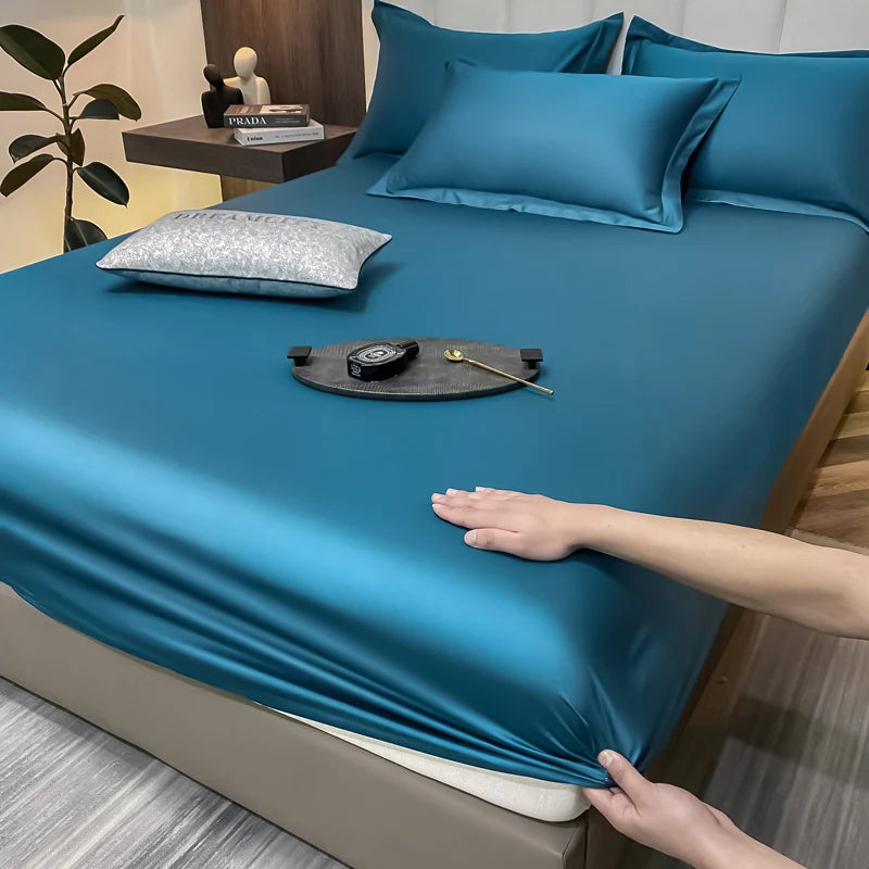 Person adjusting a blue satin sheet on a bed with a hand reaching in.